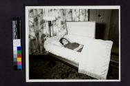 [Woman laid out in coffin by floral curtains]