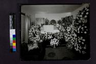 [Woman laid out in draped coffin near photograph of soldier]