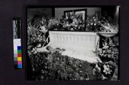 [Woman laid out with flowers pinned to dress]
