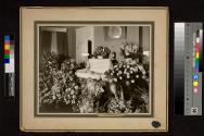 [Elderly woman laid out with "Mom" floral arrangements]