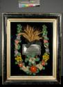 [Memorial shadow box with multi-colored chenille floral wreath, spray of dried wheat and metal coffin plate]
