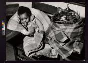 [Black child sitting by birdcage]