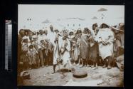 [Group of people standing around snake charmer]