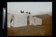 [People seated on top of city wall with mountains in background]
