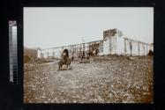 [Men riding donkeys and horses outside town wall]