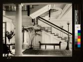 Side view of staircase showing Oriental carpets, bench, and flower arrangement