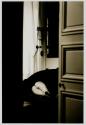 [Nude lying on couch viewed through open doorway]