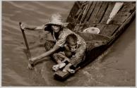 [Woman paddling boat with baby in lap]