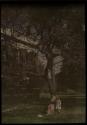 [Girl standing next to woman on tree swing in front of house]