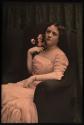[Woman in pink dress sitting in chair holding roses]