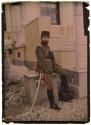 [Soldier with sword and riding crop sitting on wall]
