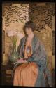 [Woman in gown and robe, posed in front of Asain screen with vase of lilies]