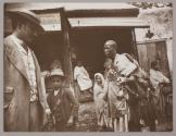 [Man holding small pots standing outside building]