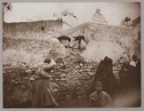 [People on and around crumbling wall]