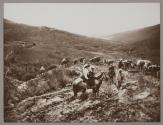 [Caravan of people on donkeys and horses in hilly area]