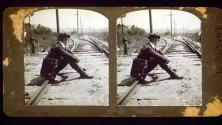 [Wallace Clendenen seated on ground by railroad tracks]