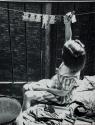 [Child hanging paper-doll clothes on clothesline]