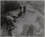 With the main blaze nearly under control, the fire fighter trains his hose nozzle into a shattered compartment.