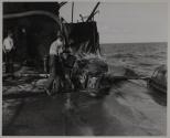 Elsewhere on the tanker, other members of the crew take steps to prevent the fire from spreading and gaining a new foothold by pouring water on burlap sacking covers over oil tanks.