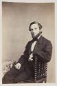 [Bearded man, seated in chair]