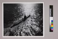 Pacific sunlight silvers the sea as a Navy submarine moves out on another patrol.