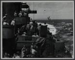 Men on ship watch explosion in distance
