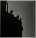[Silhouette of three men and anti-aircraft gun]