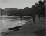 [Soldiers, dead and alive, on beach with landing craft in background]