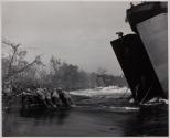 Pushing in a Jeep - A jeep from a Coast Guard-manned LST being pushed ashore through the surf at Cape Gloucester, New Britain by Coast Guard and Marines.
