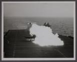 A bright ball of flame blooms on the flight deck of the carrier as gasoline fumes are ignited.