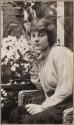 Kodak Girl model Mabel Allen Ackermann seated next to flowers