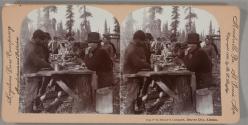 [Miners eating at a table outdoors]