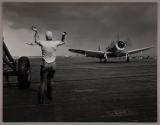 [Signaling planes as the land on deck of aircraft carrier]