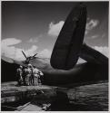 [Military personnel gathered on dock beside airplane]
