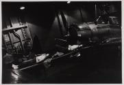[Two men sleeping by airplane on hangar deck]