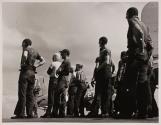 [Military personnel standing outside by airplanes]