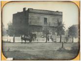 [Brick house with group of people and horse-drawn carriage in front]