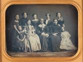 [Group portrait of ten: Elderly woman, seated, surrounded by other women, adolescent and younger girls]