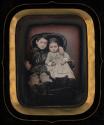 [Brother and sister, seated in upholstered chair]