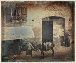 [Street scene with two women and a donkey]
