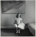 [Barbara seated in Communion dress next to bed]