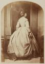 [Woman by a door, viewed from behind]