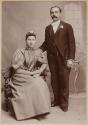 [Standing man and seated woman]