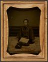 [Kneeling man with open book]