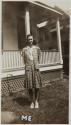 [Young woman standing by a porch]
