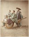 [Japanese man with two women in wheelbarrow]