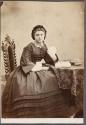 [Woman sitting in front of book]