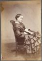 [Seated woman reading book]