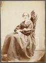 [Seated woman with hands in lap]