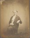 [Man with curly hair, arm resting on chair back]